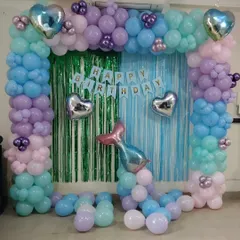 An under-the-sea mermaid theme with a beautiful balloon arch in shades of blue, purple, and pink. I used a tinsel curtain backdrop and added heart and mermaid tail foil balloons to complete the magical look.