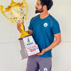 Another trophy in the cabinet. A player proudly holds the winner's trophy for the 4th Capt. Dharmpal Memorial Cricket tournament, a symbol of his hard work and our collective success.