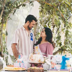 The happy couple at their baby shower celebration. This shot captures them behind a table of gifts and cake, sharing a look of love and excitement.