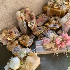 Celebrating a 40th birthday with a flourish. This collection of personalized gifts shows our dedication to making milestones feel special, with each item wrapped in a cohesive theme of gold, pink, and cream, complete with custom "Happy 40th" tags.
