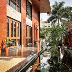 A tranquil water body runs alongside the exposed brick exterior of this contemporary villa in Hennur. This feature is central to our design philosophy of integrating natural elements like water and greenery into the living space.