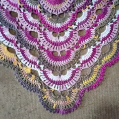 A detailed shot of the lacy, openwork sections of the Virus Shawl pattern. This design is not only visually stunning but also creates a fabric that is light and comfortable to wear.