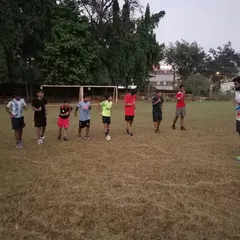 A coach addressing a group of young athletes on the field, explaining the next set of drills and setting expectations for the session.