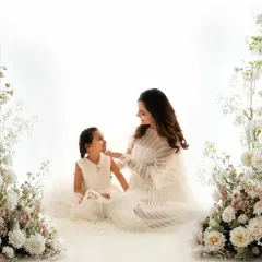 A beautiful wide shot of a mother and daughter sharing a sweet moment. The all white styling and floral arrangements create a soft, ethereal setting for this family maternity session.