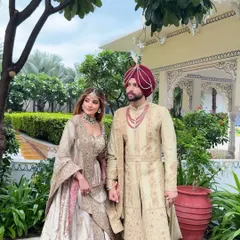 A full view of the coordinated couple's outfits. The bride's flowing lehenga and the groom's structured sherwani create a beautiful balance, showcasing how individual styles can merge into one harmonious story.