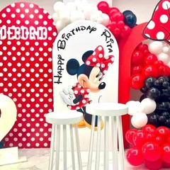 A classic Minnie Mouse theme for a 2nd birthday celebration. The setup includes red and white polka-dot backdrops, a Minnie cutout, a large number '2', and balloon arrangements in red, black, and white.