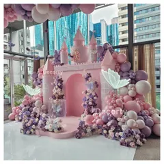 A fairytale comes to life with this stunning pink princess castle backdrop. Surrounded by a sea of pink and purple balloons and glowing butterflies, it's the perfect stage for a royal celebration.