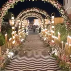A beautiful floral tunnel entrance for an evening wedding. The arches are covered in flowers and lit with candles, creating a romantic and inviting path.