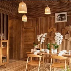 A dining room fully paneled with bamboo, creating an immersive, natural environment. Our simple, bell-shaped pendant lights hang above the table, their warm glow enhancing the rich tones of the bamboo walls and floor. This demonstrates our ability to execute complete interior concepts.