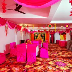 An indoor Haldi ceremony setup with the entire hall decorated in a vibrant pink theme, including chair covers, table cloths, and ceiling drapes.