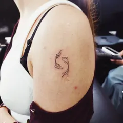 A delicate Pisces symbol, representing the duality of the zodiac sign. This fine-line tattoo is a perfect example of how a small design can have significant personal meaning.