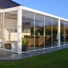 A prefabricated sunroom attached to a home, seamlessly extending the living space into the garden. This white-framed glass structure is furnished as a dining area, demonstrating a practical and popular use for our custom garden rooms.