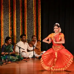 Kavya Navani in a moment of devotion during her arangetram, with the live orchestra providing the soulful musical foundation. This image captures the synergy between the dancer, the musicians, and the art form.