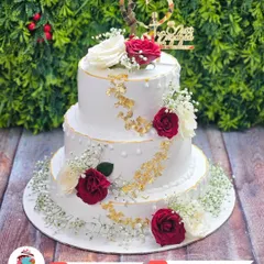 This is a classic three-tier anniversary cake, decorated with fresh red and white roses and a touch of gold leaf. It’s simple, beautiful, and perfect for celebrating your love story, whether it's for a wedding or an anniversary.
