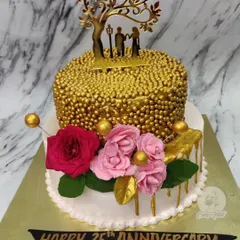 A grand celebration for a 25th anniversary! This two-tier cake features a top tier covered in gold sprinkles, a golden couple topper, and beautiful fresh roses.