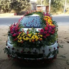 A very heavy and colorful floral decoration covering the entire hood of the car. This design uses a mix of marigolds, roses, and other flowers for a grand and traditional look.
