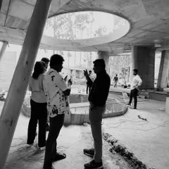 A black and white photo from a site visit, capturing a discussion amidst the raw concrete structure of a future project. This is a testament to the planning and execution that goes into every design.