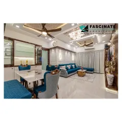 A wide view of the luxurious living and dining space at a Lodha Belair project. The design integrates a vibrant blue sofa with ornate dining furniture and a custom ceiling, showcasing our ability to blend bold colors with classic elegance.