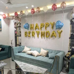 The main wall decoration with gold foil "Happy Birthday" letters, flanked by blue heart-shaped balloons and a line of ceiling balloons.