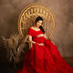 Seated in my popular peacock chair, this mother-to-be is the picture of serenity. The vibrant red ruffled gown adds a touch of drama, while the soft studio lighting creates a warm and gentle mood.
