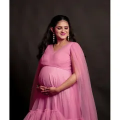 A lovely close-up shot capturing the joy of motherhood. The expecting mother is wearing our popular pink tiered gown with delicate cape sleeves.