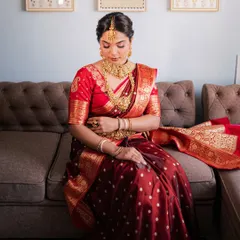 A full view of the bride seated, adorned in a classic red and gold silk saree and heavy temple jewellery. This rental captures the essence of South Indian bridal traditions.