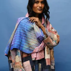 A striking portrait for Wandering Silk, where the model is wrapped in a colorful patchwork jacket and scarf. The deep blue background makes the vibrant colors and textures of the slow fashion pieces pop.