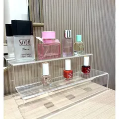 A simple acrylic tiered stand is an elegant way to organize and display perfumes and nail polishes on a vanity, keeping surfaces clear and products visible.