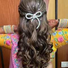 A cute and playful half-up hairstyle with soft curls and a sparkling bow accessory. This is a great option for a Sangeet or Mehendi.
