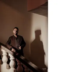 Another shot of the groom's Sangeet look, capturing the intricate details and rich texture of his embroidered jacket under dramatic lighting.