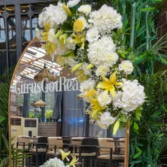 For a "Citrus Got Real" themed baby shower, I designed this elegant entrance piece. A gold framed mirror adorned with lush white hydrangeas, yellow lilies, and real lemon slices created a fresh and vibrant welcome for a zesty celebration.