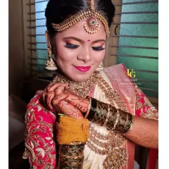 The final touches for Shruthi's muhurtham look. The warm, golden-orange eyeshadow complements her off-white and red silk saree beautifully.