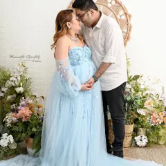 A soft and romantic moment between the expecting parents. This shot, set against a bright floral backdrop, highlights the joy and tenderness of this special time.