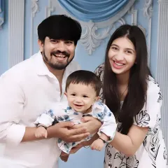 A joyful family moment, with the parents lifting their laughing baby boy, all sharing bright smiles.