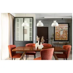 The dining area is anchored by a custom Pichwai painting of Lord Balaji, its colors harmonizing with the deep orange chairs. A live-edge walnut table and textured grey walls add a touch of rustic minimalism.