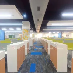 This image shows a large-scale office fit-out, demonstrating our capacity to handle extensive floor plates. The layout features rows of workstations with integrated low-height storage cabinets, designed for efficiency and easy movement. The patterned carpet tiles add visual interest and help with acoustic management in the open space.
