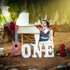 A magical outdoor first birthday shoot. The lighting and natural forest background give this classic piano setup a dreamy, fairytale quality.