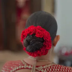 A clean and classic bridal juda, beautifully encircled with a vibrant red floral gajra. This is a signature look for the main wedding day, designed to perfectly complement a traditional red lehenga.