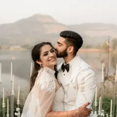 A tender kiss on the cheek against a stunning mountain and lake backdrop. This image from a white wedding ceremony is the epitome of fairytale romance and quiet elegance.