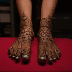 The completed bridal feet design, with fresh henna paste. The pattern is symmetrical and covers the feet beautifully, ready for the wedding festivities.
