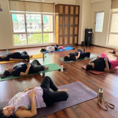 A wide view of the studio during final relaxation. Each woman is in her own space, yet there is a shared energy of peace and surrender that fills the room.