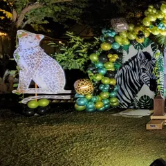 A corner of the safari party setup, featuring a large, friendly leopard cutout perched on a balloon arrangement. The use of animal-print balloons and varied green tones adds to the wild theme.