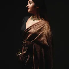 A profile shot of a model in a stunning bronze tissue saree. The look is elevated with a statement choker and sheer gloves, adding a touch of contemporary glamour to a classic drape.
