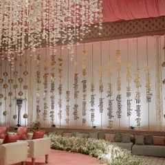 A backdrop of hanging golden Sanskrit verses, adding a deeply personal and spiritual element to the wedding decor. This detail shows how we incorporate the couple's values and story into the design.