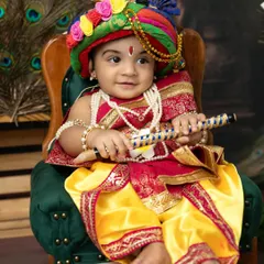 A regal portrait of a little Krishna in a colorful turban. The detailed costume and traditional props make these festival photos truly stand out.