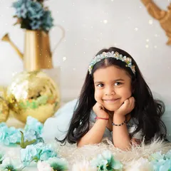 A sweet, angelic face surrounded by soft blue flowers. This close-up portrait is simple, beautiful, and timeless.
