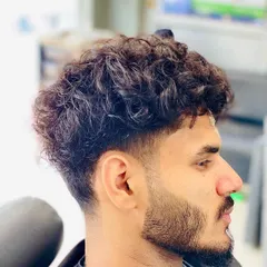 This cut is designed for curly hair, with a gentle taper on the sides to control the shape while letting the curls on top have volume and definition.