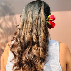 Soft, romantic waves showcasing a beautiful color melt. The addition of fresh roses makes this a perfect hairstyle for a wedding or special event.