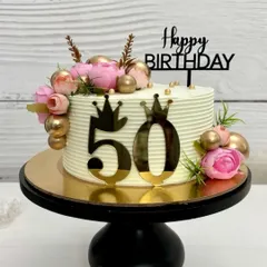 Elegant floral vibes for a fabulous 50th! This cake is decorated with pink peonies, gold spheres, and a bold '50' topper, making it a perfect centerpiece for a milestone birthday.