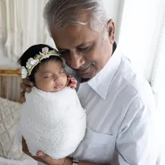 A heartwarming portrait of a grandfather holding his swaddled newborn grandchild. These multi-generational photos are treasured keepsakes for the whole family.